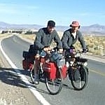 Foto van twee fietsreizigers op een verlaten woestijnweg